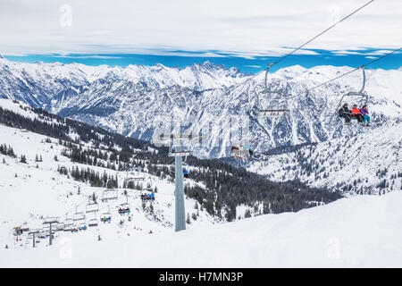 Skiers in chair lift enjoying stunning view to Bavarian Alps, Fellhorn, Oberstdorf, Germany Stock Photo