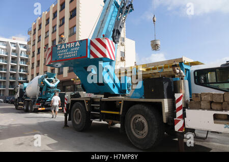 Malta, streets - Qawra. Crane used to lift blocks into position obstructs street, a common occurence as huge stones are a common Stock Photo