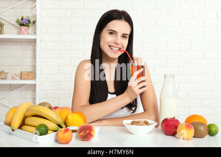 Beautiful women exists with pure skin on her face sitting at a table and eat breakfast. Asian woman eating healthy food at breakfast. Fruit, cereal and milk. Stock Photo