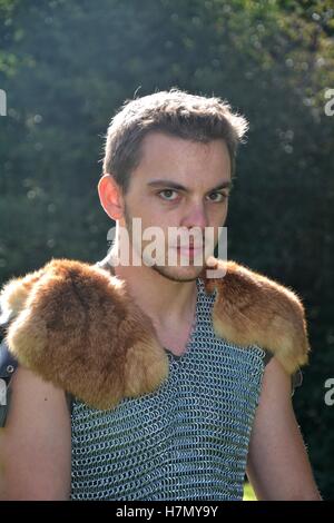 Young, medieval, black-hairy man with chain shirt and fur in shoulders Stock Photo