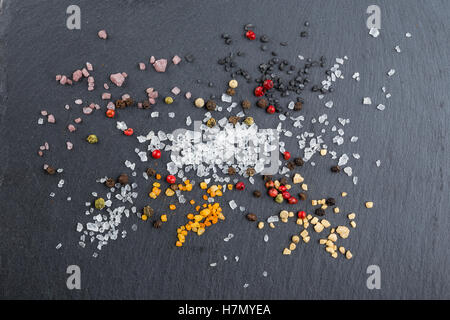 Different types of salt and pepper sprinkled on the stone background Stock Photo