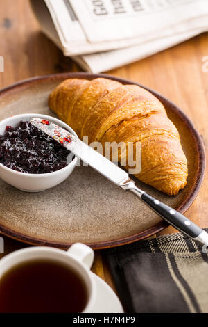 Tasty buttery croissant with jam on plate. Stock Photo