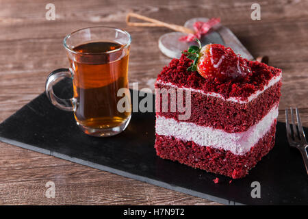 slice of red velvet cake with white frosting is garnished with strawberries close up Stock Photo