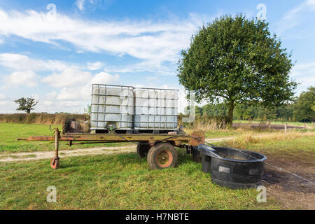 Water containers on trailer for cows in pasture Stock Photo