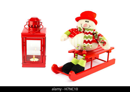 Snowman on sledge with red burning lantern isolated on white background Stock Photo