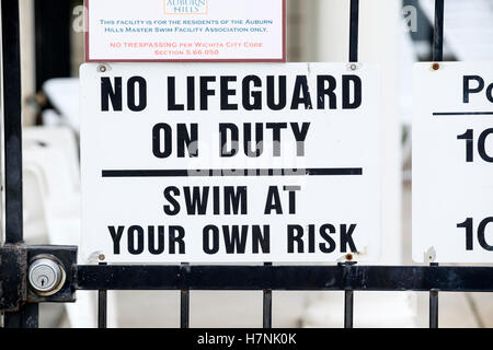 A sign stating no lifeguard on duty, swim at your own risk, for a private swimming pool for a neighborhood association. USA. Stock Photo