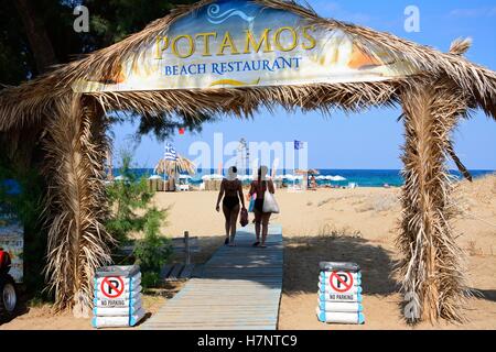 Two women walking through the entrance arch to Potamos beach, Malia, Crete, Greece, Europe. Stock Photo