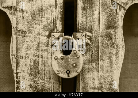 closed old metal lock hanging on wooden door hinges Stock Photo