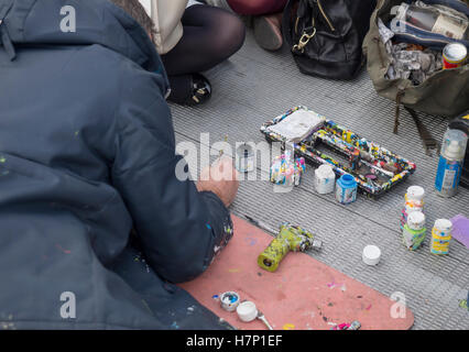 The artist Ben Wilson painting chewing gum on the Millennium Bridge in London Stock Photo