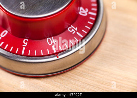 Macro view of a red kitchen egg timer showing 10 minutes on wooden background Stock Photo