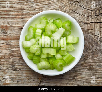 Bowl of chopped celery on wooden background, top view Stock Photo