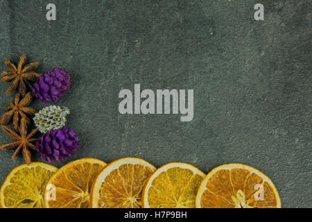 Christmas and New Year decoration with dried slices of orange, star anise and colored cones with space for text on the right. Stock Photo