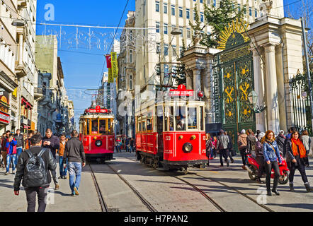 Two red trams stands on the station next to the main gate to the Galatasaray High School Stock Photo