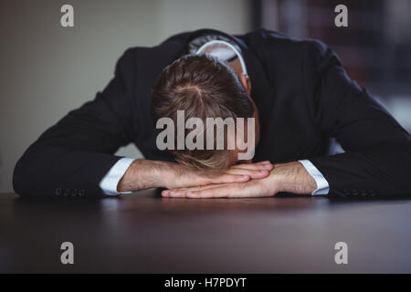 Exhausted businessman sitting with his head down on desk Stock Photo