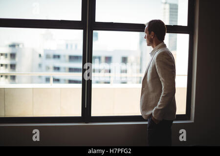 Thoughtful businessman looking through window Stock Photo