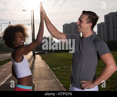 couple congratulating on morning run ginis young sporty mixed rase couple congratulating with hand five after successful morning Stock Photo