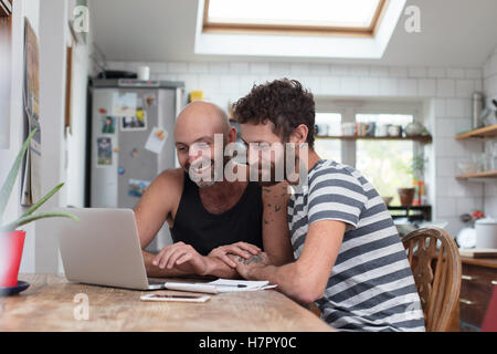 Gay couple using laptop in kitchen Stock Photo