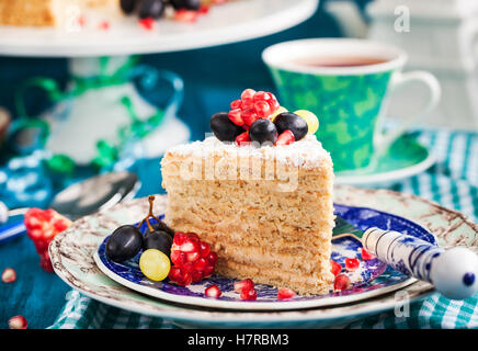 Piece of homemade honey cake decorated with fresh fruits and berries Stock Photo