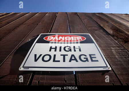 High voltage warning sign on wooden fence at a substation in New Zealand Stock Photo