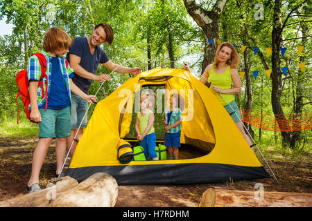 Parents putting up tent with kids on camping trip Stock Photo