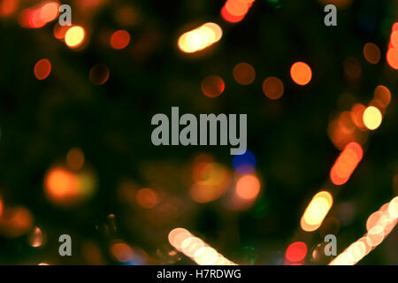 Christmas lights background. Blurred electric garland on Christmas tree. Red, green, yellow, orange, blue glow