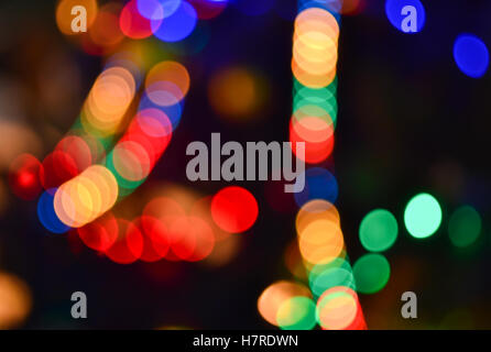 Christmas lights background. Blurred electric garland on Christmas tree. Red, green, yellow, orange, blue glow in dark