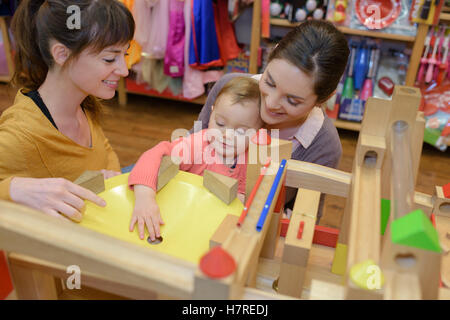 mother and daughter with attractive vendor in toy store Stock Photo
