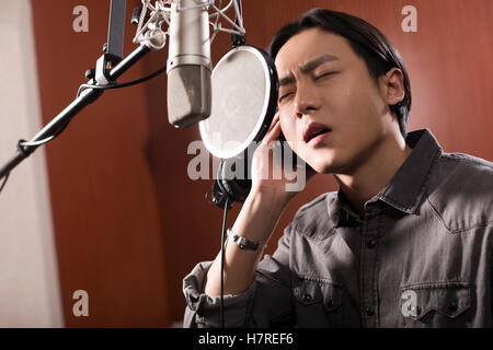 Young Chinese man singing in recording studio Stock Photo