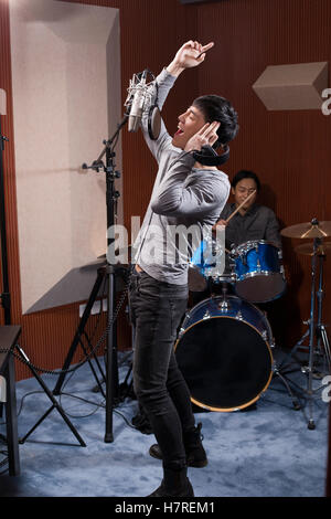 Young Chinese man singing in recording studio Stock Photo