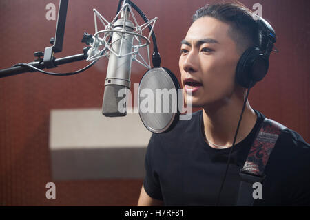 Young Chinese man singing in recording studio Stock Photo