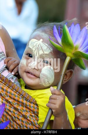 Yangon, Myanmar - 16 November 2014.  Young child in mother's sling with bo-leaf thanaka design on forehead, Stock Photo