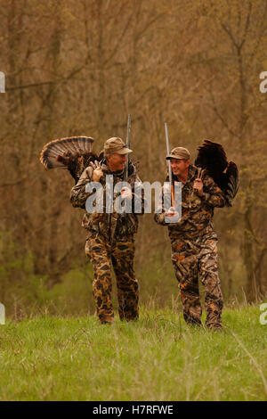 Two Turkey Hunters Walking And Carrying Dead Turkeys Stock Photo