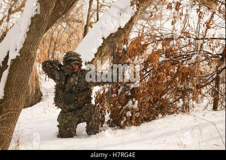 Male Bowhunter Draws Bow In Snow While Deer Hunting Stock Photo