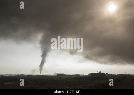 Qayyarah, Niniveh, Iraq. 8th Nov, 2016. 08/11/2016. Qayyarah, Iraq. Smoke from a burning oil valve rises from within the town of Qayyarah, Iraq. Oil wells in and around the town of Qayyarah, Iraq, we set alight in July 2016 by Islamic State extremists as the Iraqi military began an offensive to liberated the town.For two months the residents of the town have lived under an almost constant smoke cloud, the only respite coming when the wind changes. Credit:  ZUMA Press, Inc./Alamy Live News Stock Photo