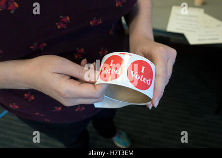 Election Official holding a roll of "I Voted" stickers which are passed out to voters as the leave the polling area for  November 8, 2016 national election in McNeely Hall on the Campus of St Thomas University. St Paul Minnesota MN USA Stock Photo