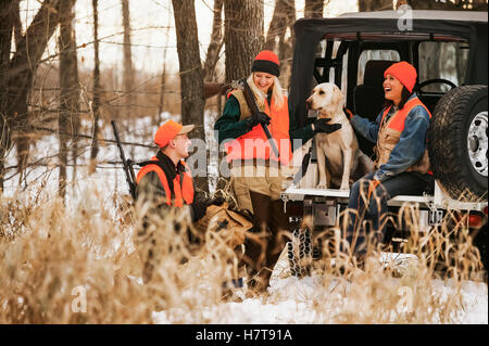 Young Male And Female Hunters On Tailgate With Yellow Lab Stock Photo