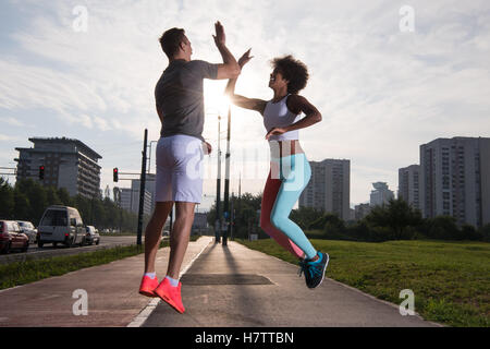 couple congratulating on morning run ginis young sporty mixed rase couple congratulating with hand five after successful morning Stock Photo