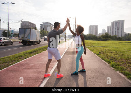 couple congratulating on morning run ginis young sporty mixed rase couple congratulating with hand five after successful morning Stock Photo