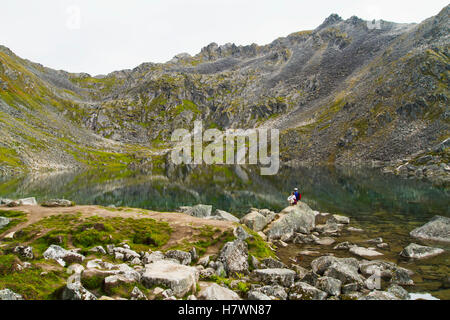 Pair of hikers stop to enjoy the view at Gold Cord Lake in Hatcher Pass. Southcentral Alaska. Summer. Stock Photo