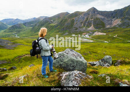 Woman photographs the old mine buildings of Independence Mine in Hatcher Pass up the trail to Gold Cord Lake, Alaska in Summer. Southcentral Alaska. Stock Photo