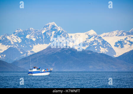 A small fishing boat on the waters of Main Bay, with the Chugach Mountains in the background, Prince William Sound, Whittier, Southcentral Alaska, USA Stock Photo
