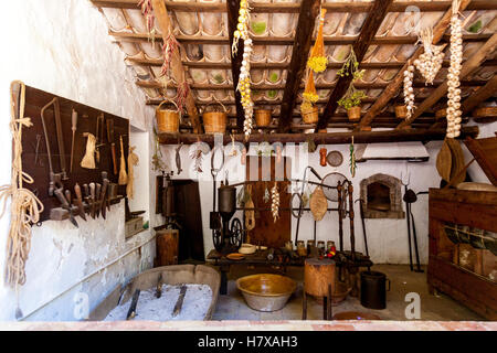 Old-fashioned kitchen with ancient dishes and hanging garlic and onion Stock Photo