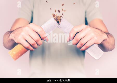 Quit smoking - male smoker breaking giant cigarette Stock Photo