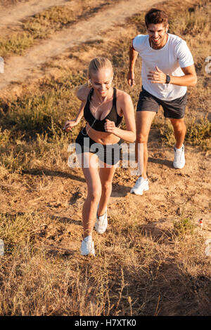 Athletic female runner and male fitness model running together outdoors Stock Photo