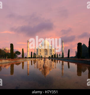 Nobody present as Taj Mahal glows beautifully at sunset reflected in front garden water fountain pool of water under a dramatic Stock Photo