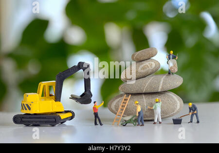 Pebbles stack and figurines of construction workers Stock Photo