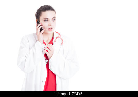 Serious medic female with medcial uniform having a conversation on mobile phone isolated on white with copyspace Stock Photo