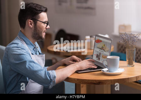 Pleasant young man working on laptop. Stock Photo