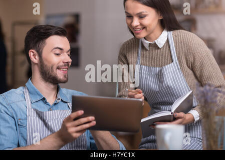 Emotional young couple making notes and using tablet. Stock Photo
