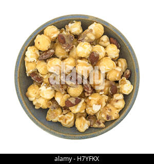 Top view of an old stoneware bowl filled with glazed gourmet popcorn with almonds and pecans isolated on a white background. Stock Photo